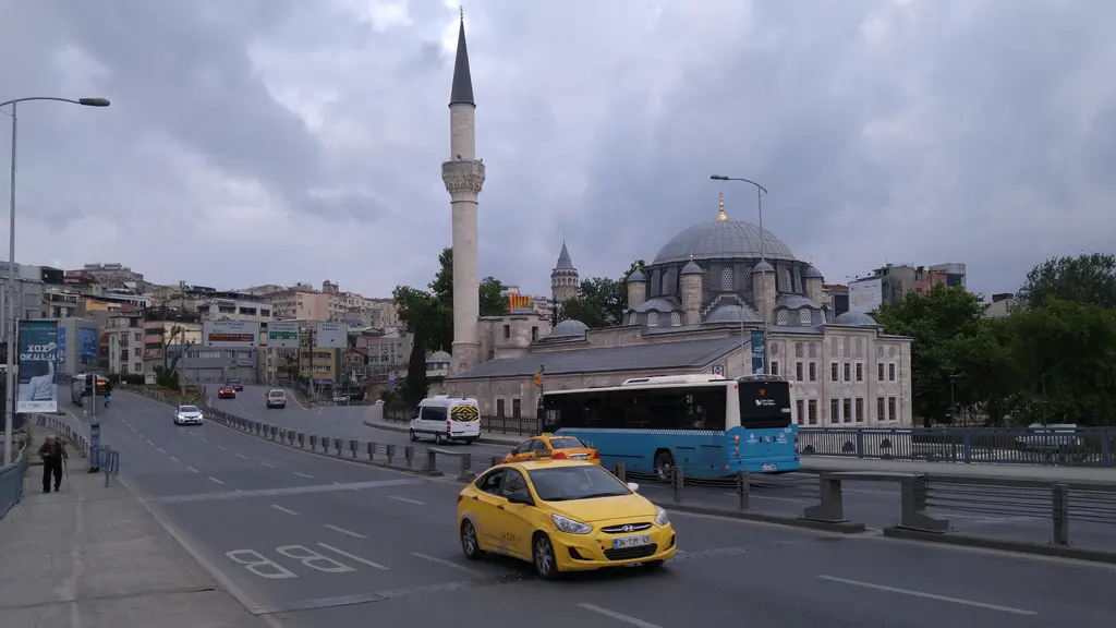 Atatürk Köprüsü yolundan Azapkapı Sokullu Mehmed Paşa Camii; önde taksi ve otobüsler, ortada kubbeli cami ve minare, bulutlu gökyüzü.