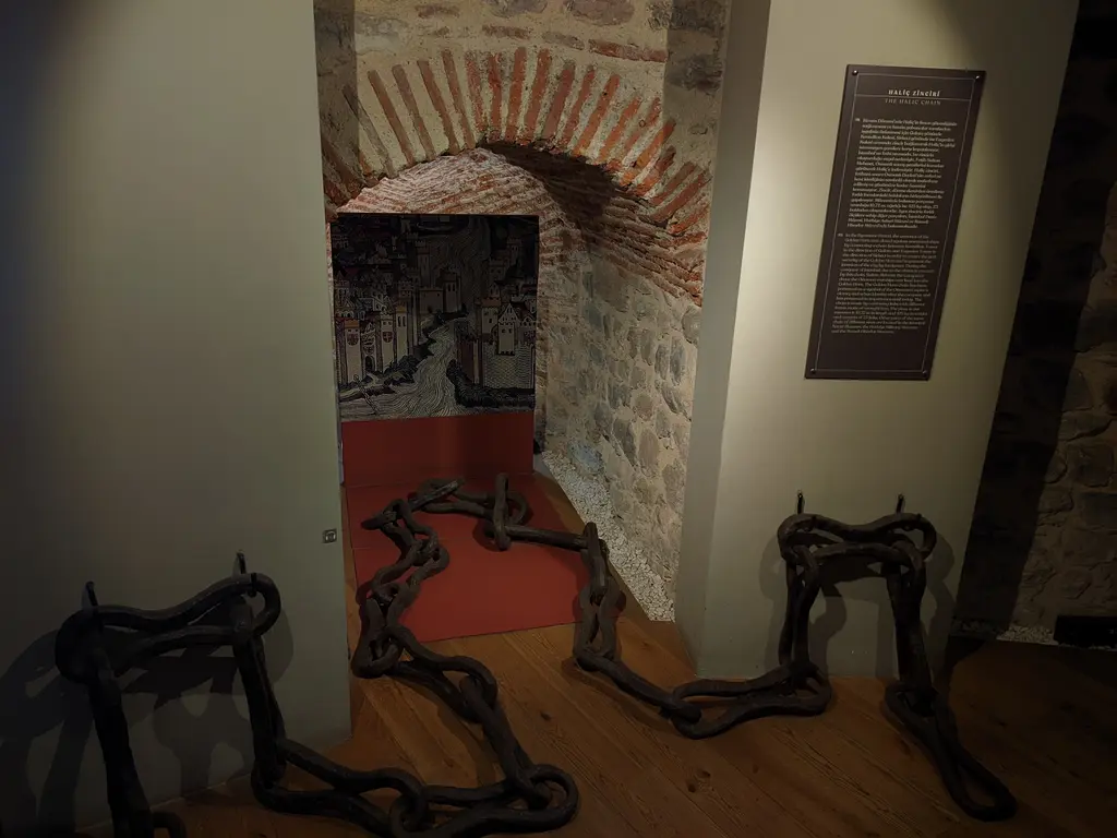 Galata Kulesi'nde sergilenen Haliç zinciri; ahşap zemine uzanan iri demir halkalar, arkada taş ve tuğla örgülü kemerli niş.