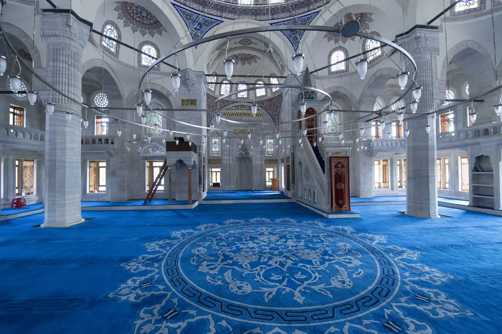 Azapkapı Sokullu Mehmed Paşa Camii'nin harimi; desenli mavi halı, taş payeler, mahfiller, kalem işli kubbe ve sıra sıra pencereler.