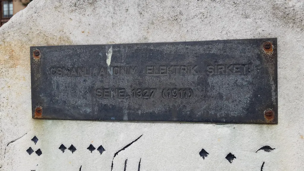 Santralistanbul'da tarihi levha; taş üzerinde paslı vidalı metal plaka, kabartma "Osmanlı Anonim Elektrik Şirketi Sene 1327 (1911)" yazısı.