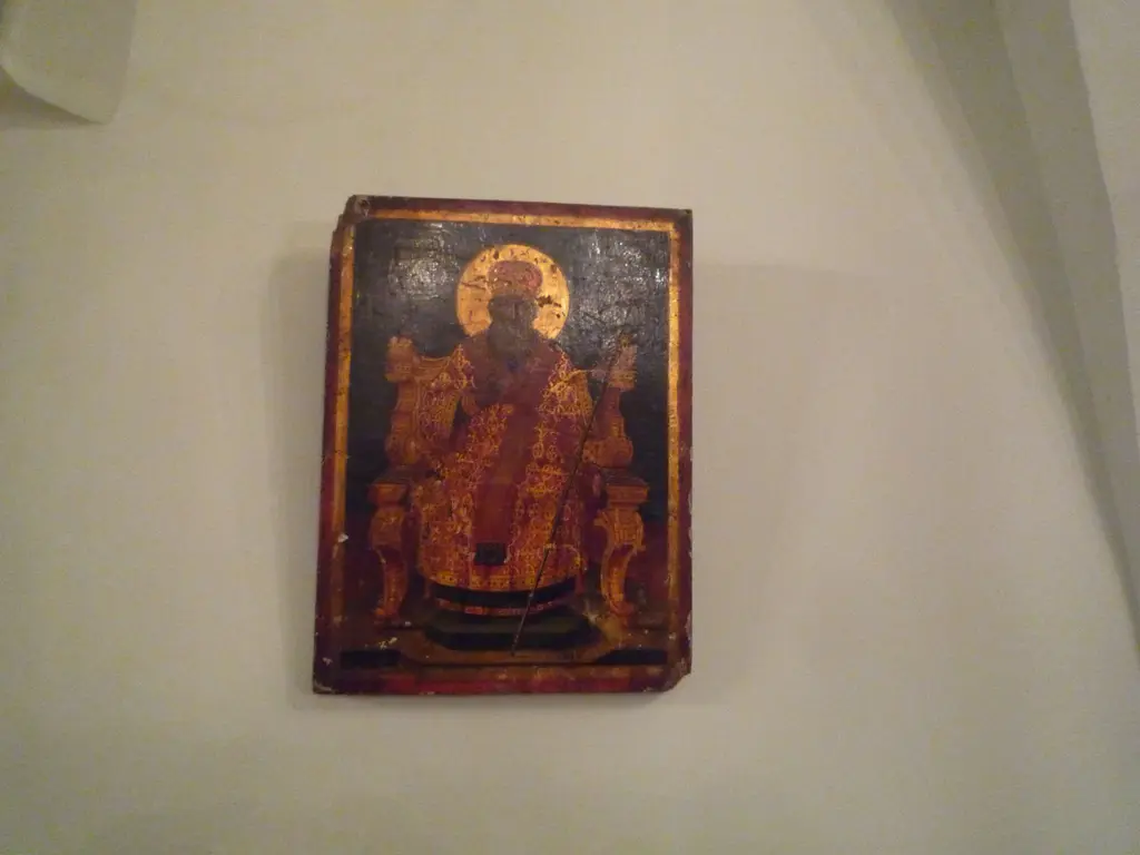 Kanlı Kilise'nin duvarında küçük ahşap ikona; kırmızı zemin üzerinde tahtta oturan, başı haleli bir aziz ve eskimiş yaldız.