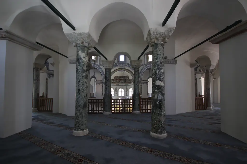 Küçük Ayasofya Camii'nin üst kat galerisi; beyaz beşik tonozlu koridor, yeşil beyaz damarlı mermer sütunlar ile oyma başlıkları, lacivert gri halı ve ahşap korkuluk.