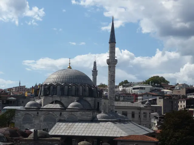 Eminönü'nde Rüstem Paşa Camii'nin çatılardan görünümü; yaldızlı alemli kurşun kubbe, kafesli pencereli kasnak, tek şerefeli minare ve önde son cemaat yerinin eğimli kurşun çatısı.