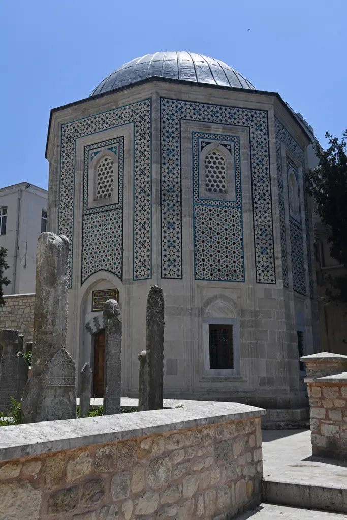Mahmut Paşa Türbesi; sekizgen gövde, cephelerde firuze ve lacivert çini kakma, kurşun kubbe, önde mezar taşları ve alçak taş duvar.