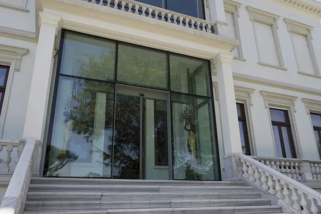 Sakıp Sabancı Müzesi girişi; beyaz cepheye açılan büyük cam kapı, iki yanda mermer korkuluklu basamaklar.