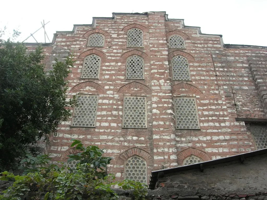 Gül Camii'nin kuzey cephesi; dört sıra kemerli ve petek gözlü pencere, kademeli alınlık, almaşık tuğla taş örgü, solda bir ağaç.