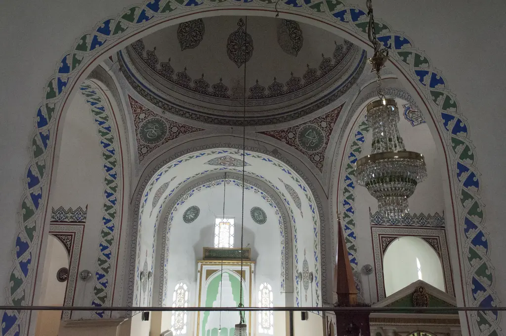 Atik Mustafa Paşa Camii'nin içinde mahfilden apsise bakış; iç içe büyük kemerler, kubbeye geçişte pandantifler, mavi yeşil kalem işi bantlar ve uzakta mihrap nişi.