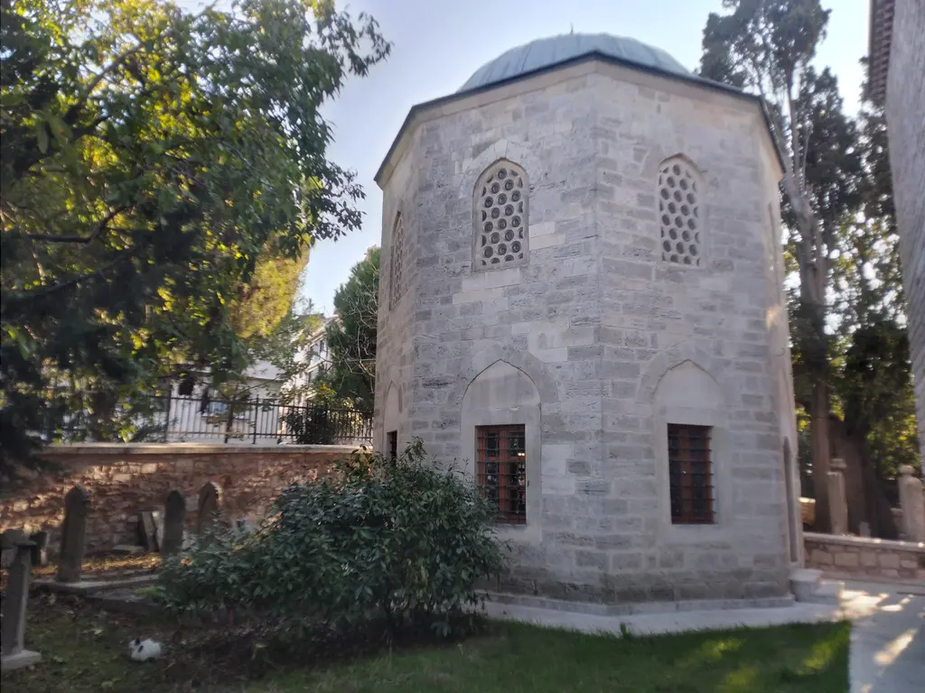 Rum Mehmed Paşa'nın türbesi; yeşil bahçe içinde sekizgen taş yapı, kurşun kubbe, pencereler ve arkada ağaçlar.