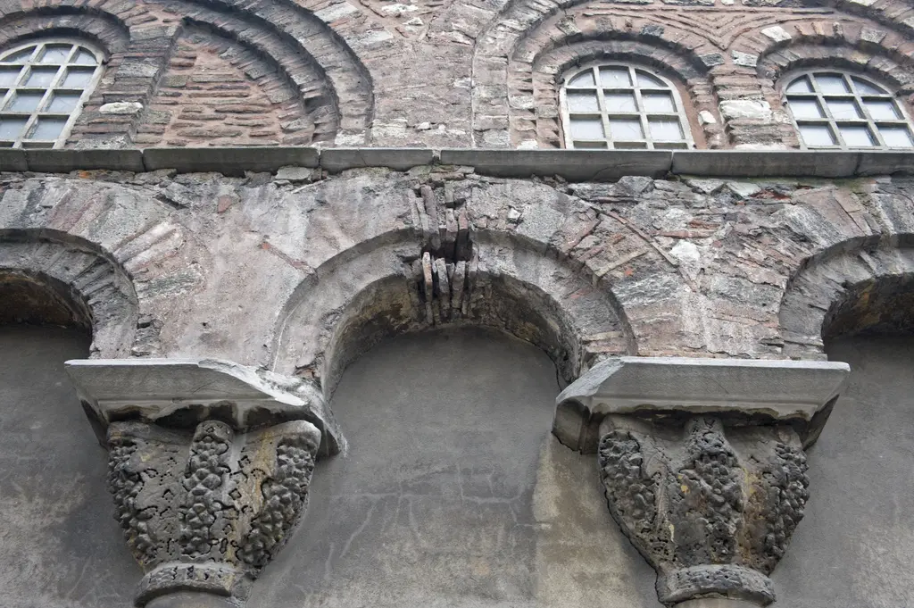 Vefa Kilise Camii'nin dış narteksinde iki ağır mermer başlık; üzüm salkımı motifleri, düz impost blokları, taşıdıkları kararmış tuğla kemerler ve üstte kemerli pencere sırası.