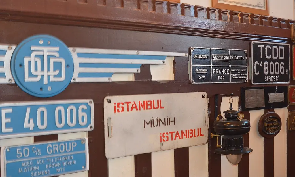 İstanbul Demiryolu Müzesi'nde plaket duvarı; mavi kanatlı TCDD arması, E 40 006 numaralı lokomotif plakası, kırmızı harfli İstanbul Münih güzergâh levhası ve emaye istasyon plakaları.