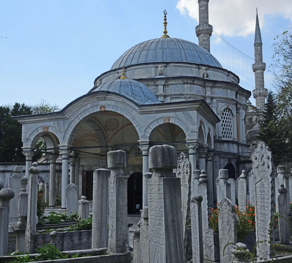 Mihrişah Valide Sultan Türbesi'nin revaklı girişi; mermer sütunlar, yuvarlak kemerler, kubbe ve önündeki hazirede sıralı mezar taşları.