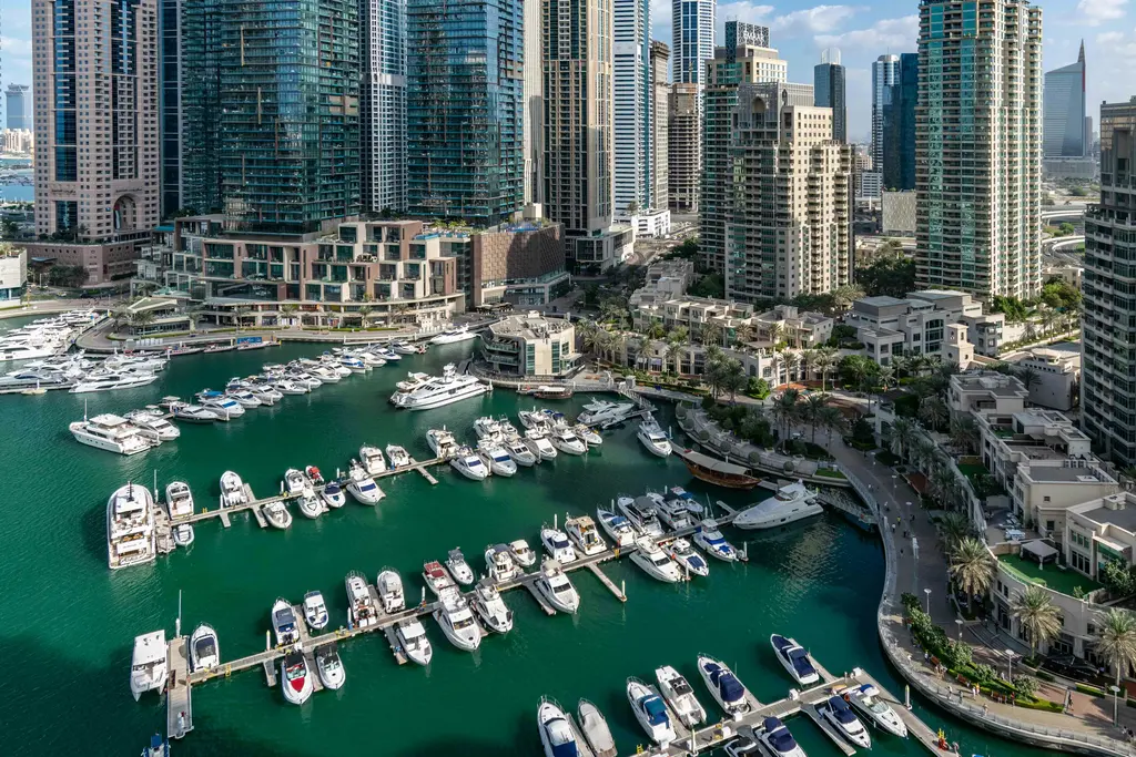 Dubai Marina; gökdelenlerle çevrili yat limanı, su üzerindeki yansımalar ve yürüyüş yolu.