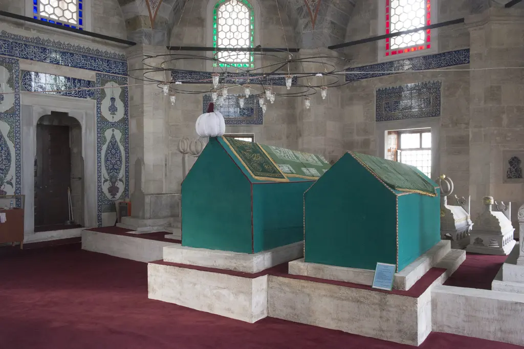 Sokullu Mehmed Paşa Türbesi'nin içi; yeşil örtülü iki sanduka, çini kaplı duvarlar, renkli vitraylar ve kırmızı halı.