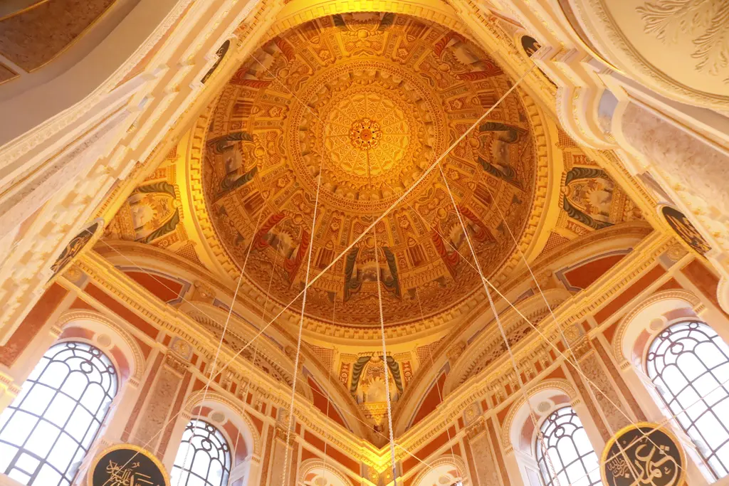 Ortaköy Camii'nin kubbesi içeriden; turuncu ve altın tonlarında kalem işleri, ortada göbek ve çevresinde pencereler.