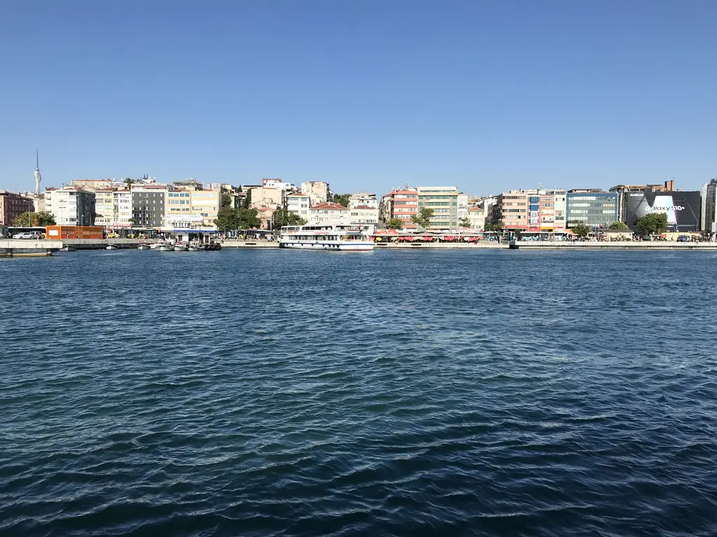 Denizden Kadıköy kıyısı; mavi su, kıyı boyunca sıralanan renkli binalar ve iskeleye yanaşmış vapurlar.