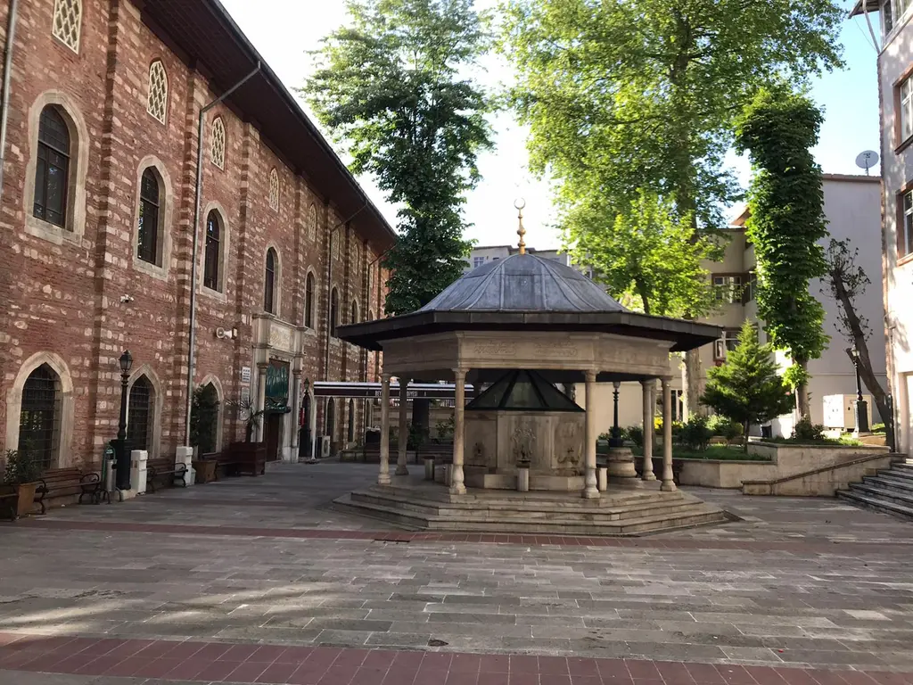 Arap Camii'nin avlusu; uzun tuğla cephe, avlu kapısı, önde taş zemin ve arkada sıralanan pencereler.