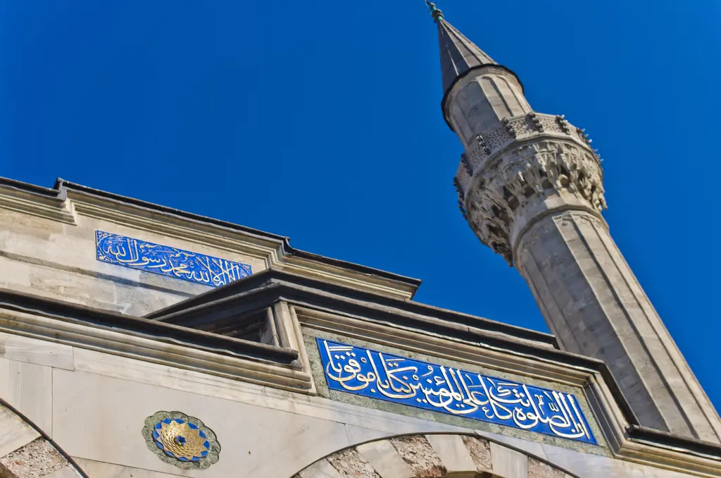 Sokullu Mehmed Paşa Camii'nin minaresi; taş gövde, mukarnaslı şerefe, konik külah ve altında mavi zeminli çini hat kuşağı.