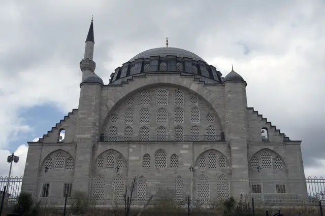 Edirnekapı'da Mihrimah Sultan Camii dışarıdan; dev sivri kemerli ana cephe, üstünde tek kubbe, solda tek şerefeli minare ve bulutlu gökyüzü.