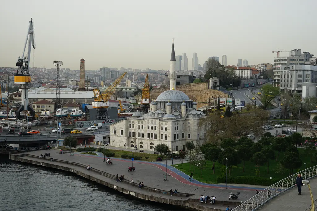 Haliç kıyısında Azapkapı Sokullu Mehmed Paşa Camii; önde rıhtım ve deniz, ortada kubbeli cami ve minare, arkada vinçler ve Beyoğlu yamacı.