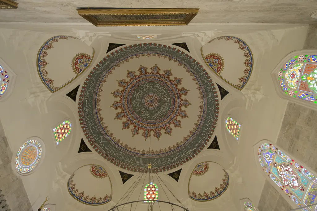 Şemsi Paşa Camii'nin kubbesi; ortada çok renkli kalem işi göbek, köşe trompları ve renkli cam pencereler.