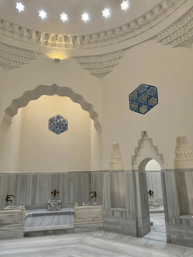 Çinili Hamam'da yerinde kalan çiniler; eyvan kemerinin duvarında iki altıgen mavi firuze İznik panosu, altında mermer kurnalar ve pirinç musluklar.