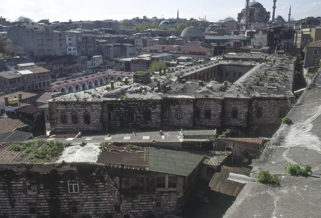 Büyük Valide Han'ın çatısından hanın kendi gövdesi; uzun iki katlı taş kanatlar, otlanmış düz damlar, oluklu sacla kapatılmış ekler ve solda revaklı bir avlu.
