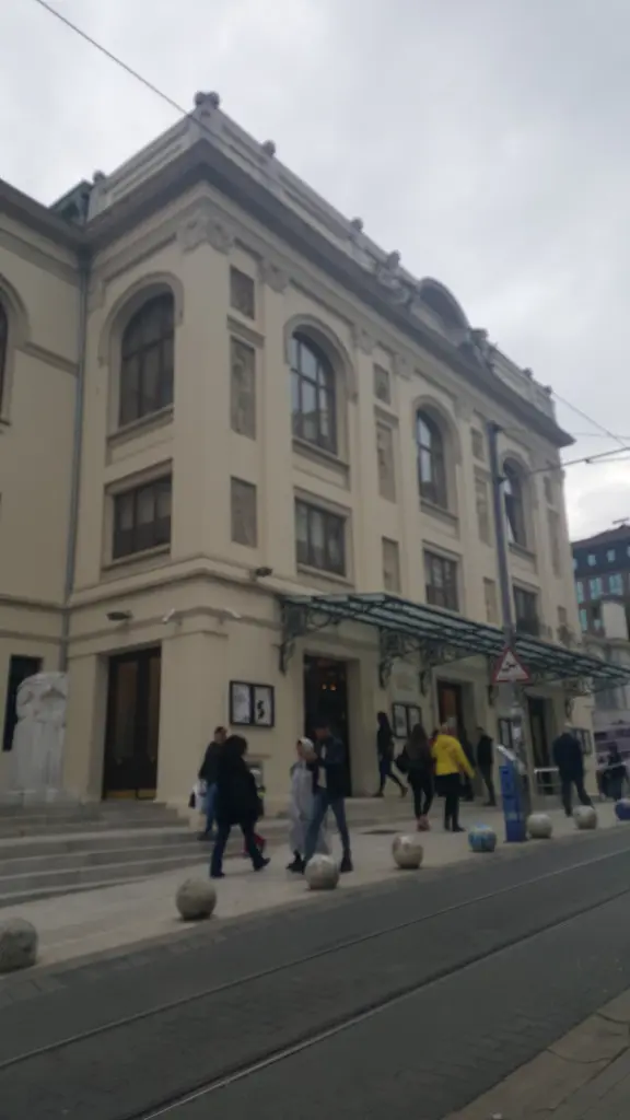 Süreyya Operası köşeden; krem rengi cephe, kemerli pencereler, girişe çıkan basamaklar ve yanındaki apartmanlar.