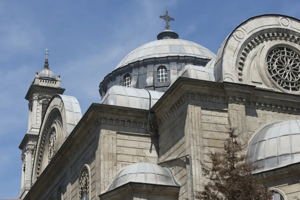 Aya Triada Kilisesi; ortada pencereli kasnaklı kubbe, yanında çan kulesi, önde yarım kubbe ve gül pencereli alınlık.