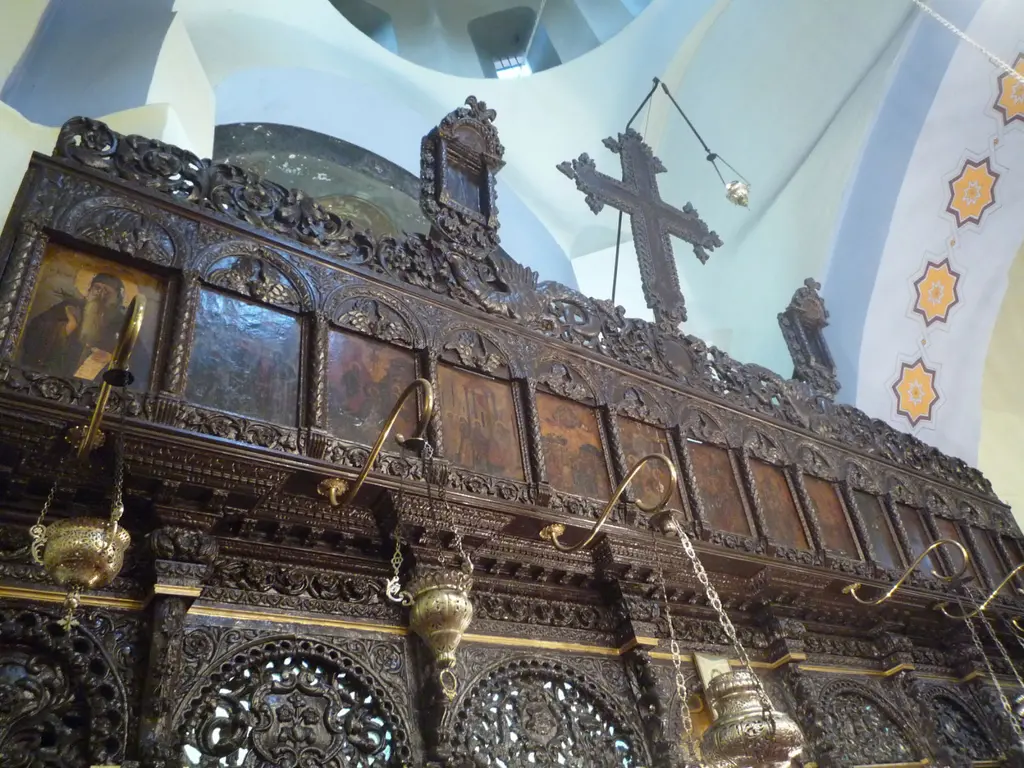 Kanlı Kilise'nin ikonostasisi; koyu renkli oymalı ahşap panolar, sıra sıra ikonalar, tepede büyük bir haç ve yanda yıldız desenli kemer.