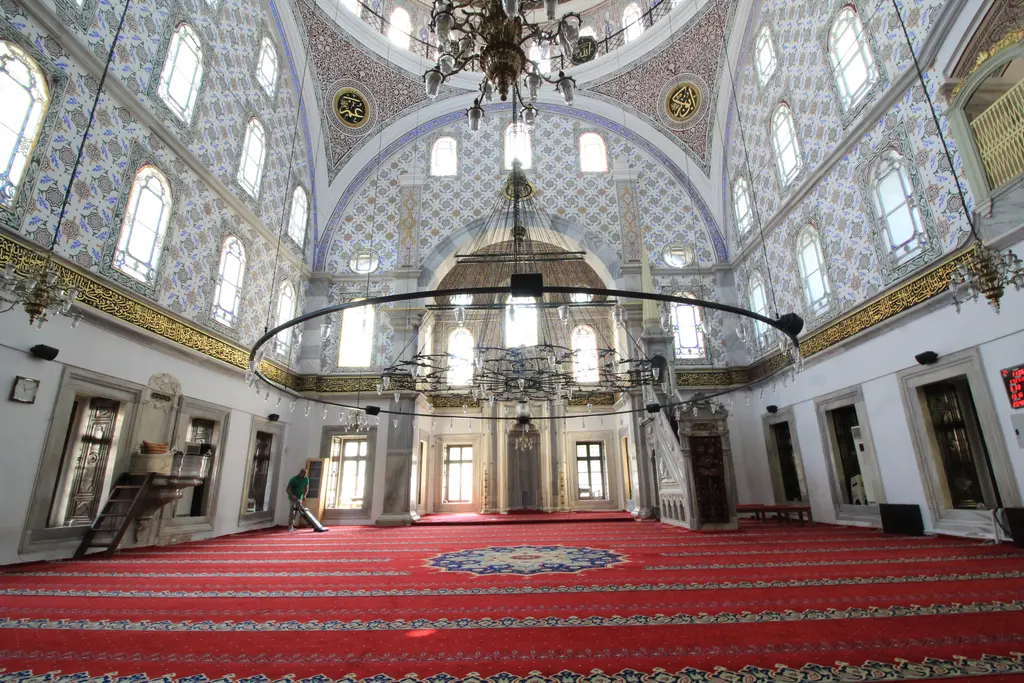 Selimiye Camii'nin harimi; kırmızı halı, kemerli pencereler, mermer mihrap ve minber, tavandan sarkan avize çemberi.