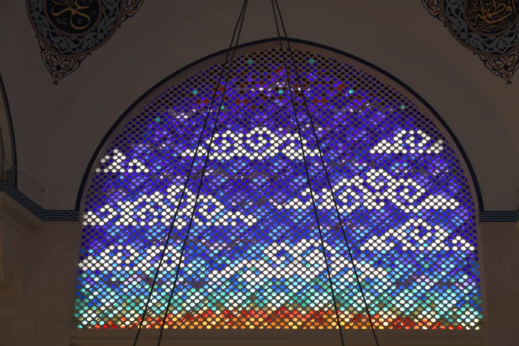 Büyük Çamlıca Camii'nde renkli pencere; kemerli açıklıkta mor, mavi ve beyaz camlardan bulut deseni.