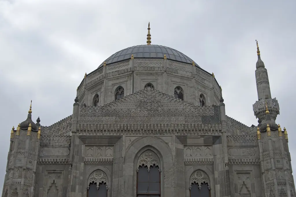 Pertevniyal Valide Sultan Camii'nin kuzeydoğu cephesi; kurşun kubbe, sivri kemerli pencereler, oyma süslü taş yüzey ve minare.