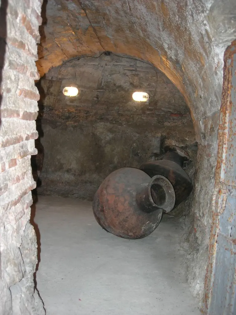 Kanlı Kilise'nin altında taş ve tuğla örgülü kripta odası; yerde duran büyük toprak küpler ve tavanda iki lamba.