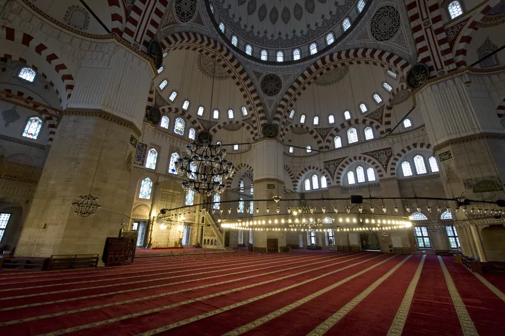 Şehzade Camii'nin harimi; kırmızı halıda saf çizgileri, büyük demir avize, kırmızı beyaz almaşık kemerler ve yukarıda kalem işi bezeli kubbe.