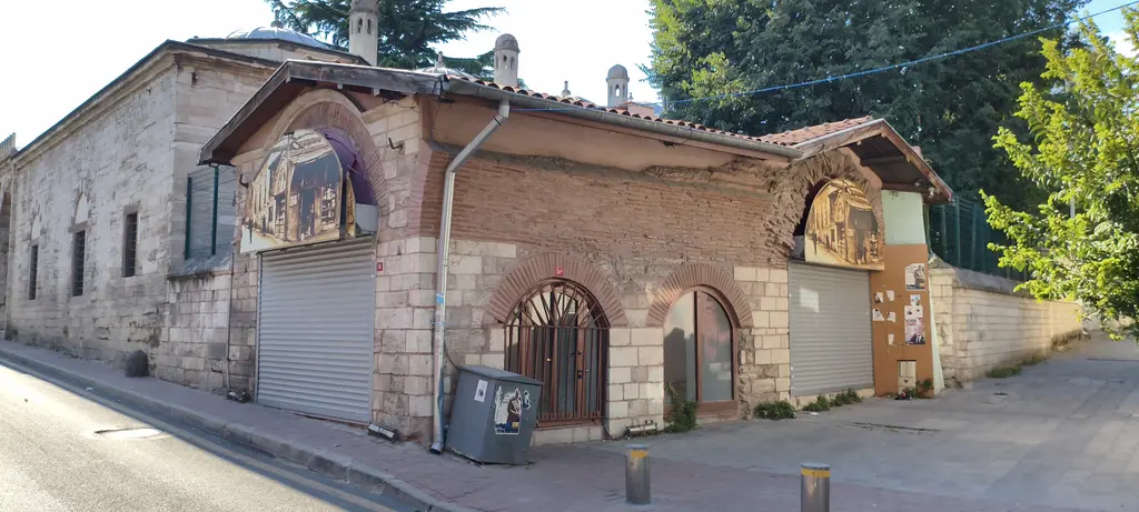 Haseki Sultan Külliyesi'nin yakınında tonozlu bir yapı; taş ve tuğla cephe, kemerli pencereler, kepenkli dükkân ve kaldırım.
