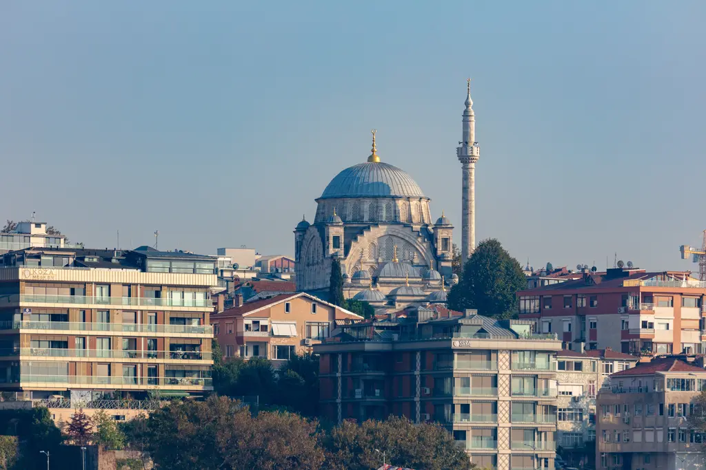 Üsküdar'da Ayazma Camii; denizden görülen yamaçta kurşun kubbe ve tek minare, önünde apartmanlar ve ağaçlar.
