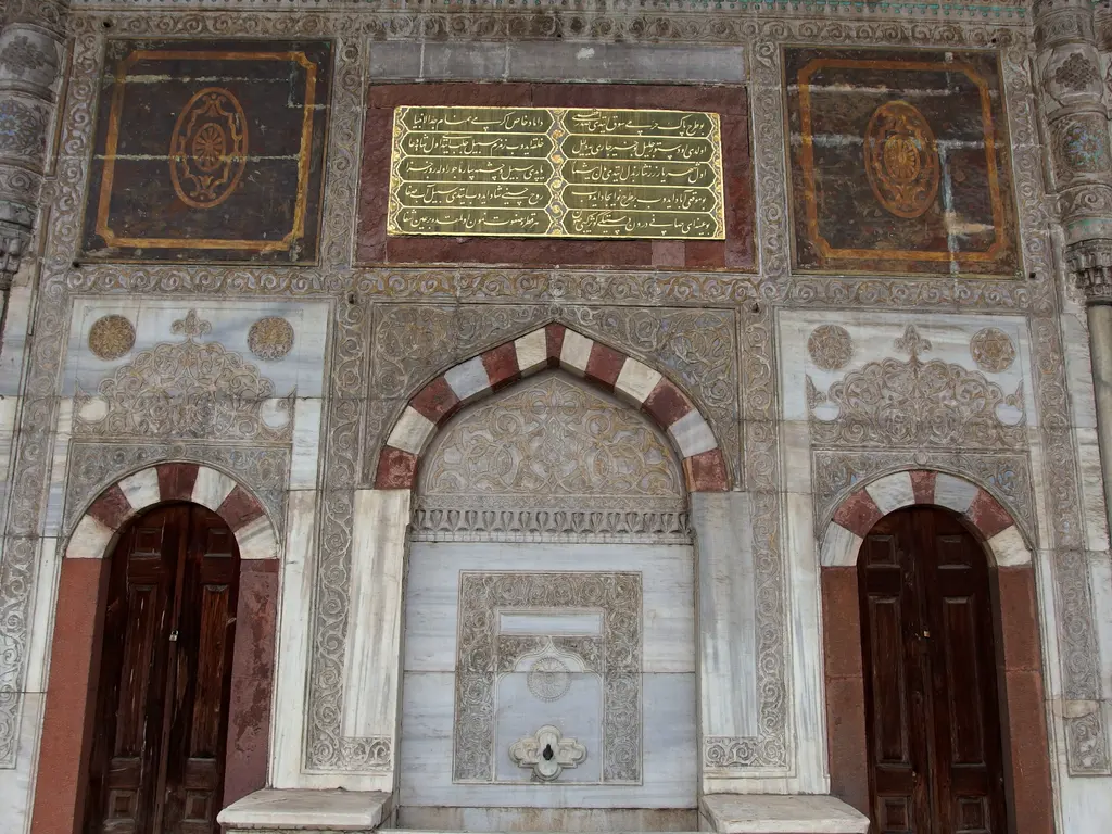 Çeşmenin kapılı cephesi; ortada çeşme nişi, iki yanda ahşap kanatlı birer kapı, üstlerinde altın yaldızlı kitabe levhaları.