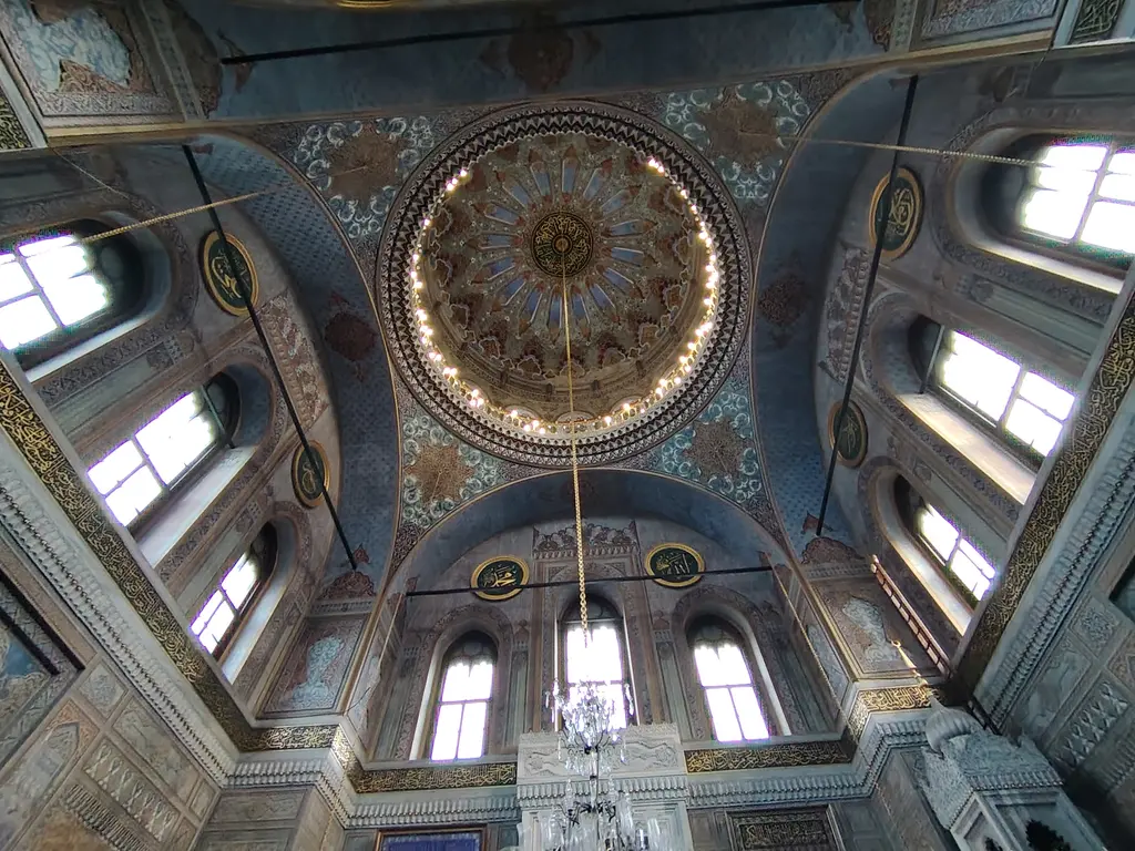 Pertevniyal Valide Sultan Camii'nin kubbesi içten; mavi ve altın kalem işi, ortada yazı madalyonu, kasnaktaki pencereler.