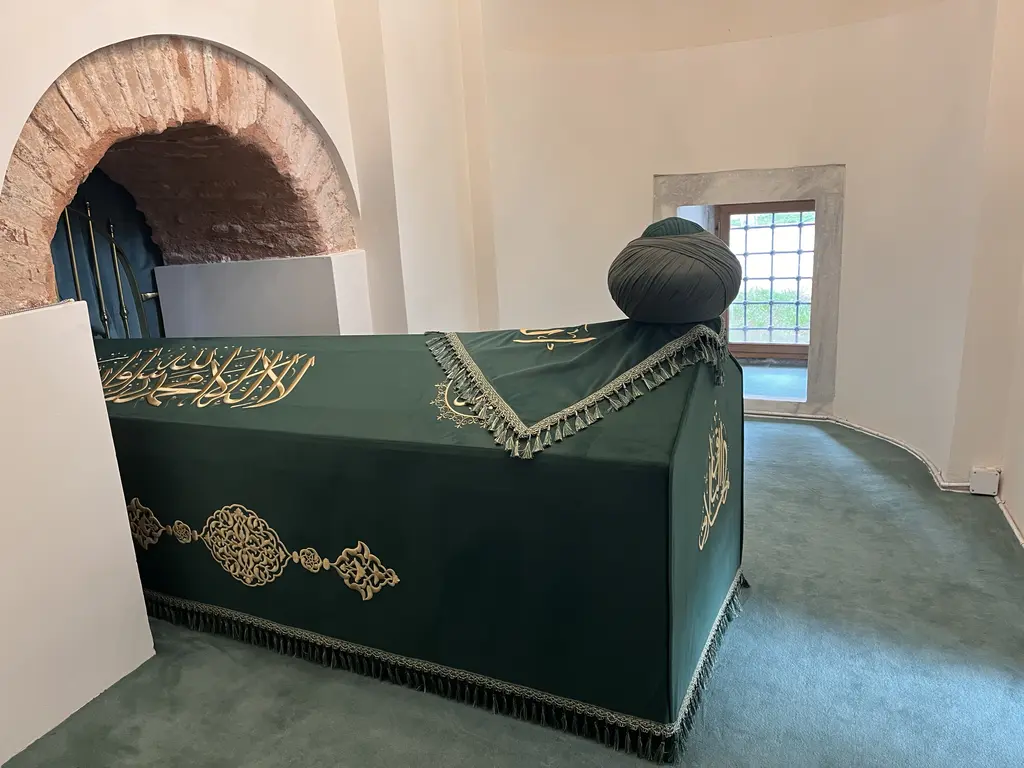 Atik Mustafa Paşa Camii'nde Hz. Câbir makamının içi; altın sırma yazılı yeşil örtülü sanduka, baş tarafında sarık, yanda açığa çıkarılmış tuğla kemer ve sıvalı beyaz duvarlar.