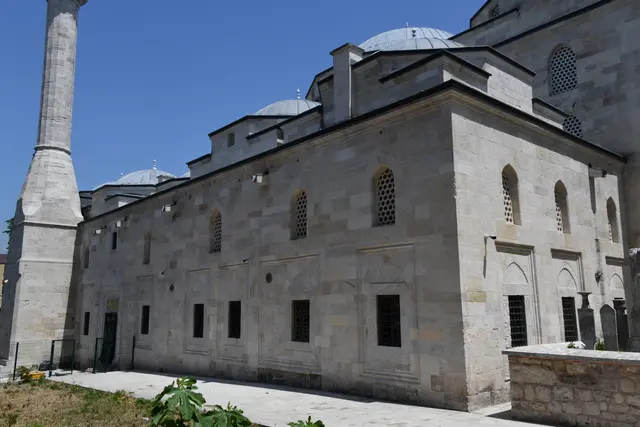 Mahmutpaşa'da Mahmut Paşa Camii; kesme taştan uzun yan cephe, iki sıra pencere, basamaklanan kubbeler, solda taş minare ve önde mezar taşları.
