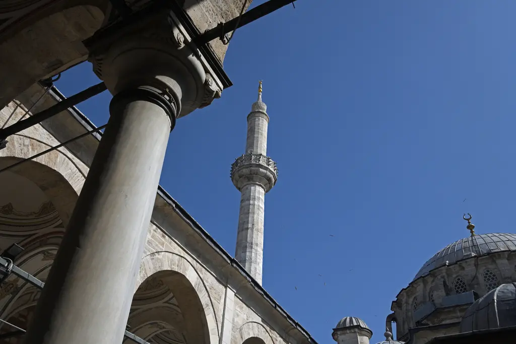 Laleli Camii'nde avludan minare; öndeki mermer sütun, arkasında çokgen gövdeli minare, şerefe ve mavi gökyüzü.
