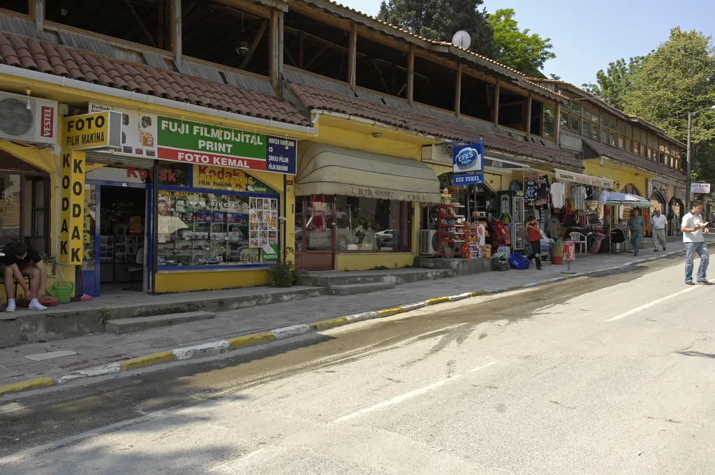 Şile'de alışveriş caddesi; tek katlı dükkân sırası, saçak altında vitrinler, kaldırımda yürüyen insanlar ve ağaçlar.