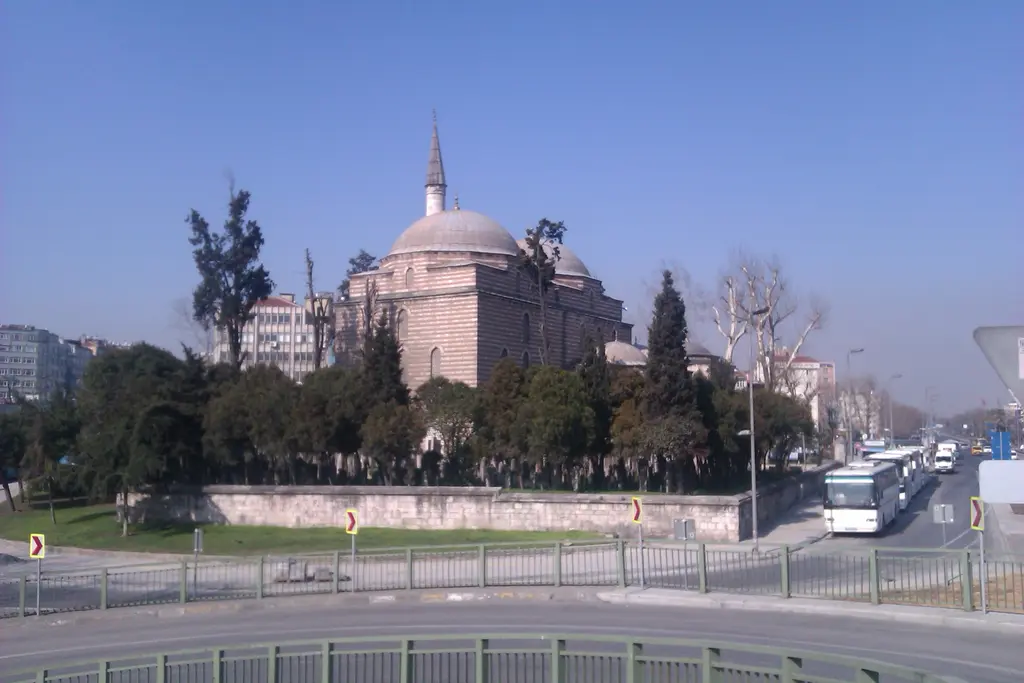 Aksaray kavşağından Murat Paşa Camii; kubbeli cami, minare, önde geniş cadde, otobüsler ve ağaçlarla çevrili avlu.
