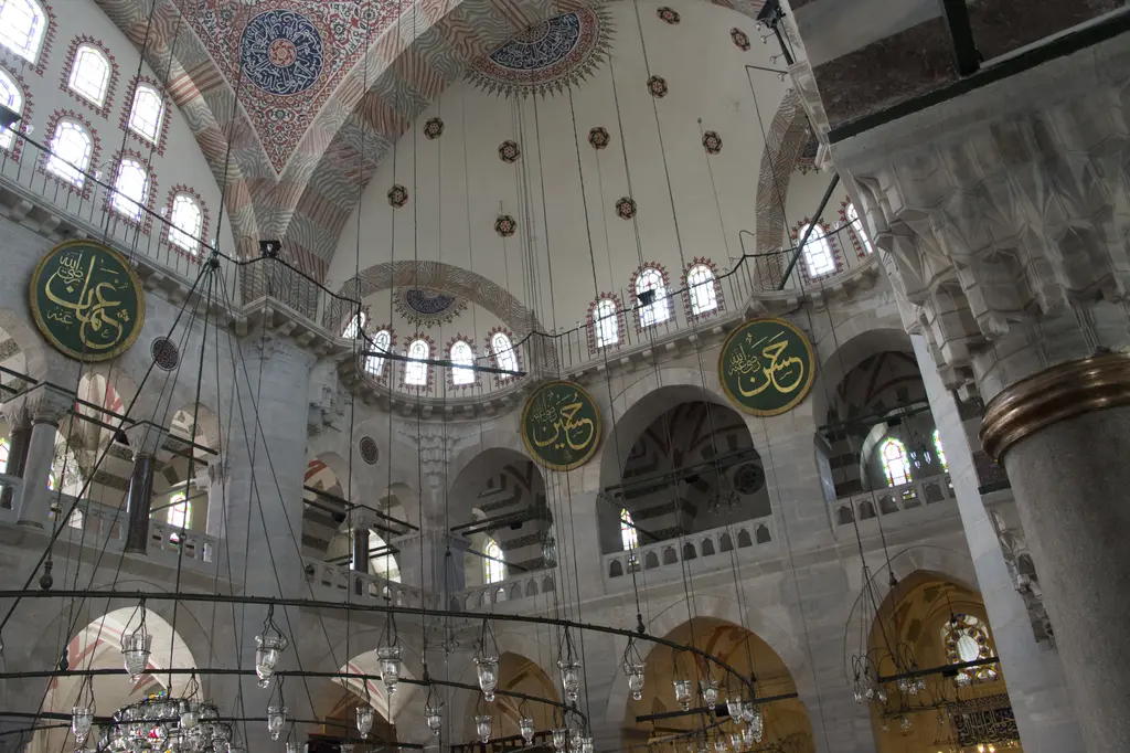Kılıç Ali Paşa Camii'nin içi; pandantifler, kemerli galeriler, sıra sıra pencereler ve duvarlarda yuvarlak hat levhaları.
