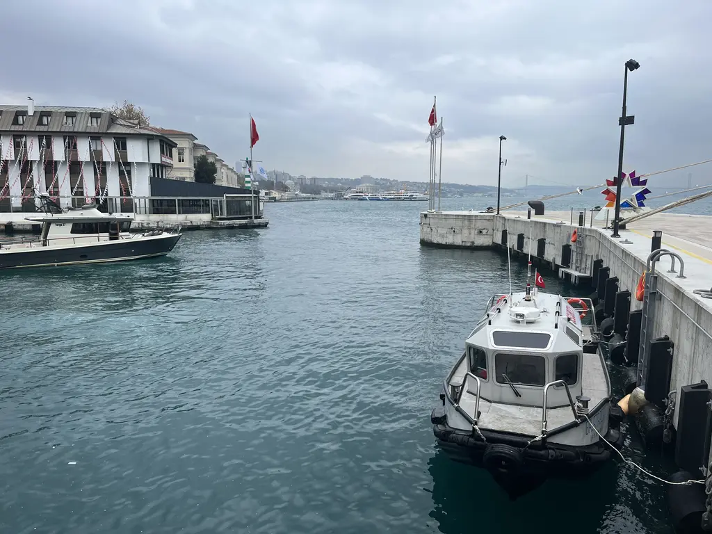 Galataport'ta iskele; önde bağlı küçük tekne, solda kıyı binaları, ortada beton iskele ve bayrak direkleri.