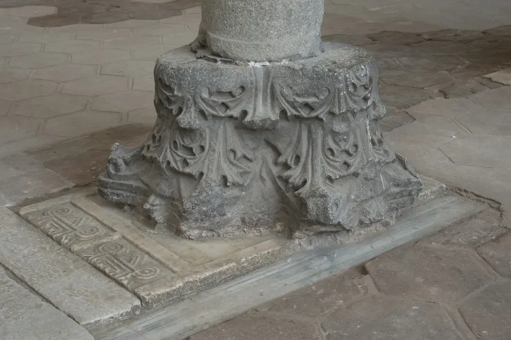 Zeminde sütun tabanı; kalın gövdenin altında oyma akant yapraklarıyla bezeli taş kaide ve çevresinde taş döşeme.