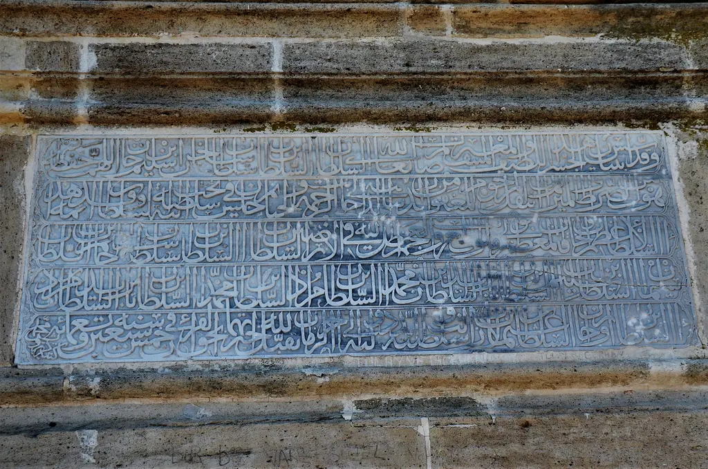 Kanuni Sultan Süleyman Köprüsü'nde ikinci kitâbe; mermer levha üzerinde aşınmış satırlar ve taş çerçeve.
