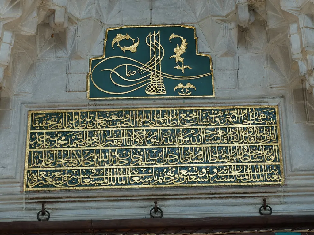 Nişancı Mehmed Paşa Camii'nin taçkapısı üstünde yeşil zemin üzerine yaldızlı tuğra ve altında dört satırlık yaldızlı kitabe.