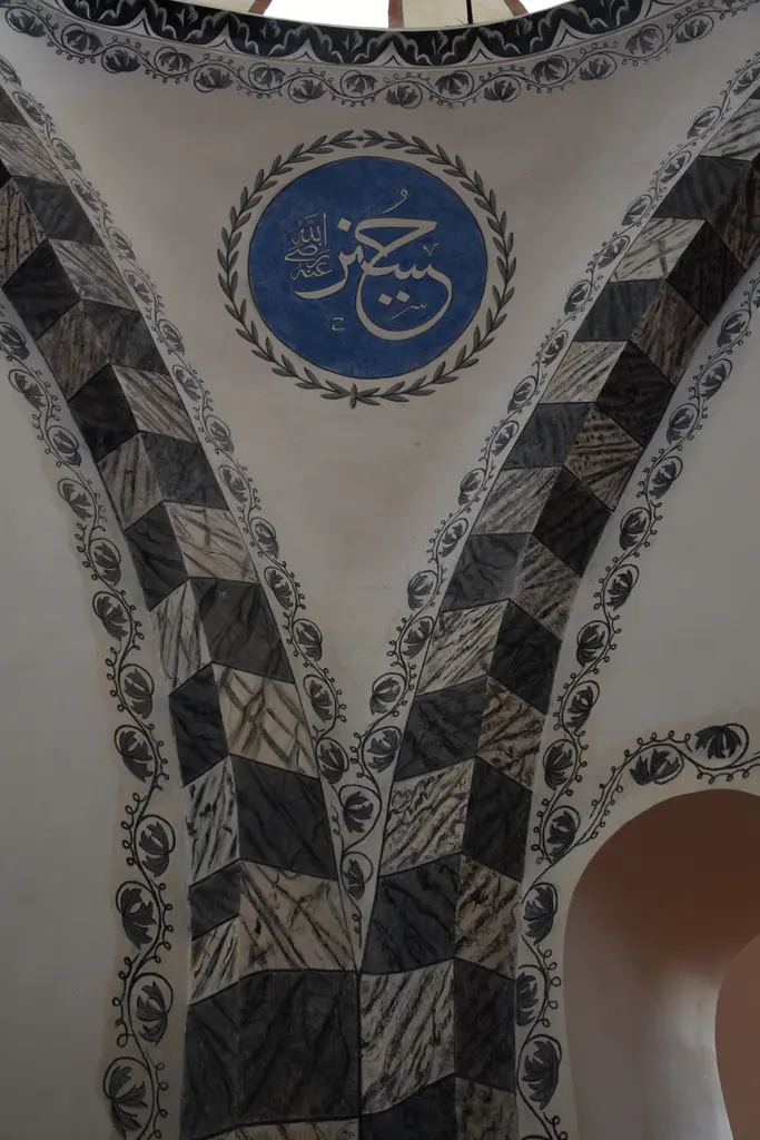 Zeyrek Camii'nde tavan detayı; mavi zeminli yuvarlak madalyonda beyaz hat yazısı, çevresinde siyah beyaz damalı kemer bordürü ve krem renkli sıva.
