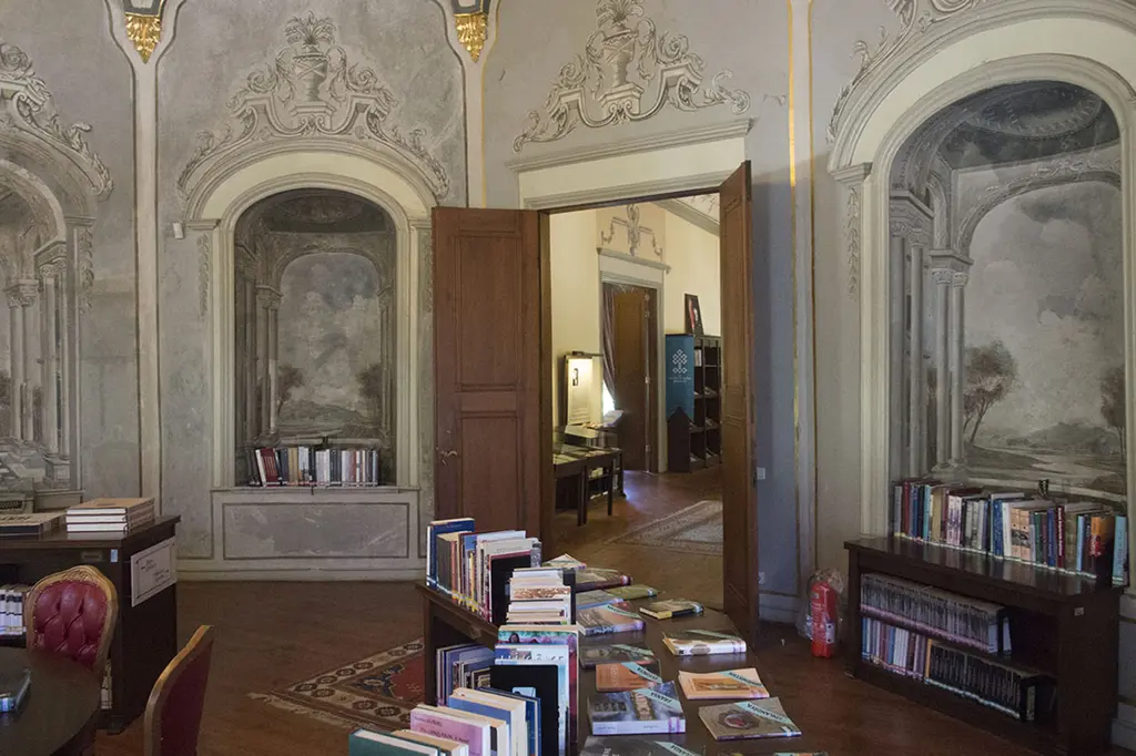 Alay Köşkü'nün iç odası; barok çerçeveli duvar nişleri, açık ahşap kapı, kitap rafları ve masada dizilmiş kitaplar.